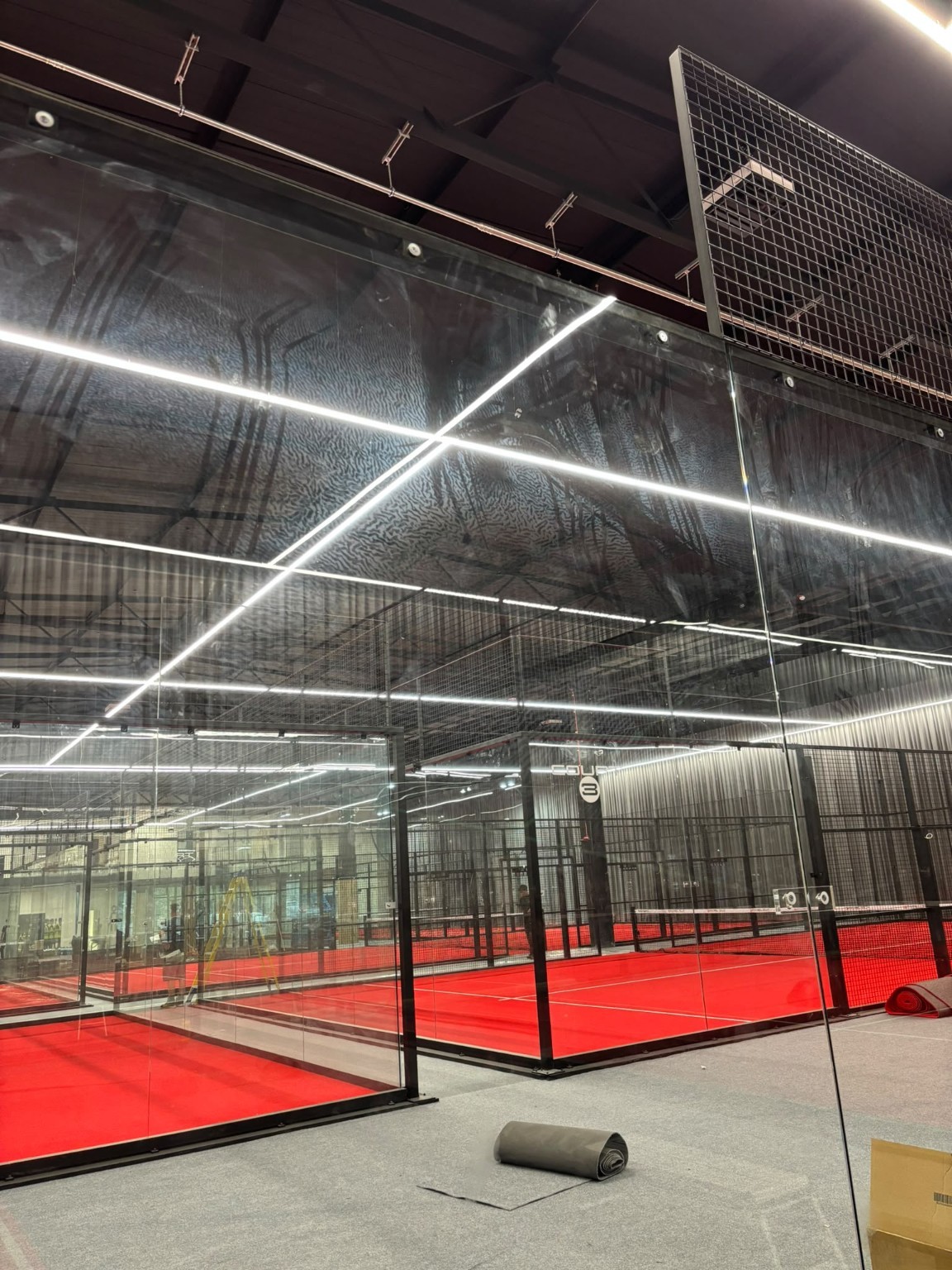 Padel court glass with visible ball marks before cleaning